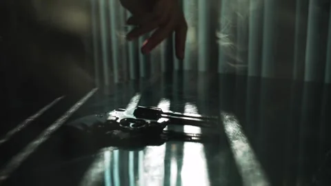 Man hand spin shiny black revolver on a table and backlight by dramatic sunlight Vídeos de archivo 294151673