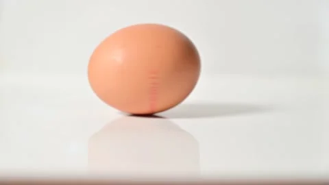 Man hand spinning raw egg on the table Stock Footage 180644118