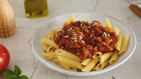 A man hand sprinkle parmesan cheese in pasta penne with bolognese sauce Stock Footage 196598491