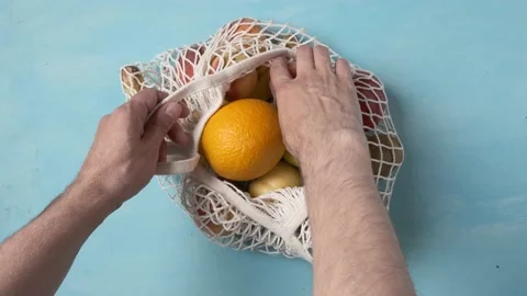 Man hand take peach from string reusable bag with tropical summer fruits Stock Footage 203235812