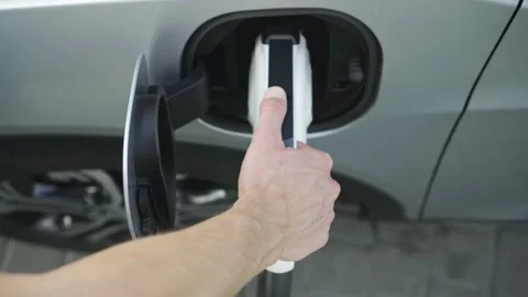 Man hand takes and hold power cable charging electric car vehicle Stock-Footage 144535398