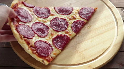 Man hand takes a large slice of pepperoni pizza close up Stock Footage 123458123