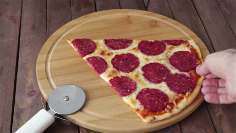 Man hand takes a large slice of pepperoni pizza from cutting board Stock Footage 124682471