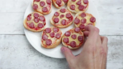 Man hand takes mini pizza sandwich from white plate first person view close up Stock Footage 125866010