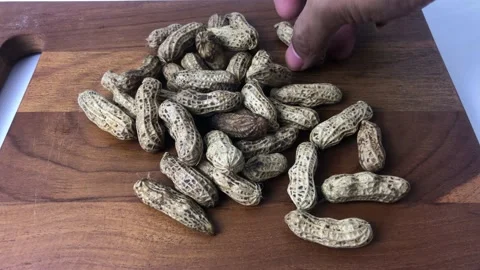 Man hand takes a shelled peanut in a wooden plate Stock Footage 236767788