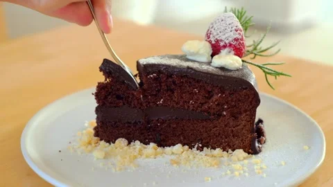 Man hand taking a bite of moist, delicious chocolate cake with a spoon Stock Footage 252012572
