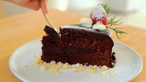Man hand taking a bite of moist, delicious chocolate cake with a spoon Stock Photos