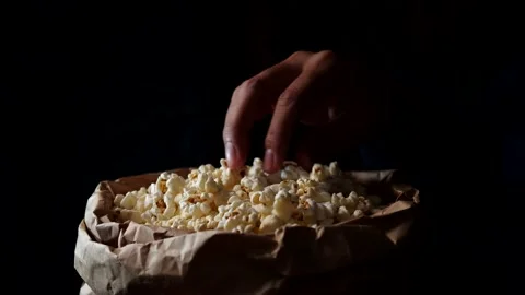 Man hand taking popcorn from paper box. Eating pop corn at home Stock Footage 143843313
