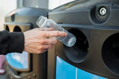 Man hand throwing plastic bottle into recycling bin Stock Photos