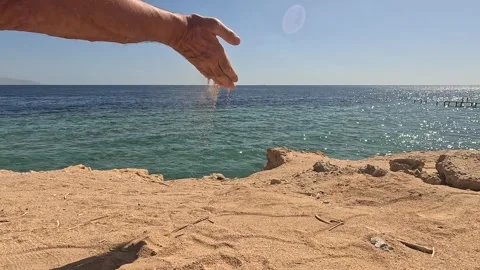 Man hand throwing sand over Sinai Peninsula sea. Person releasing dust towards Stock Footage 330325540