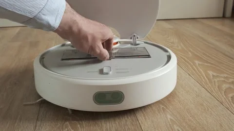 Man hand throws trash out of dust bin of white robot vacuum cleaner Stock Footage 242419412