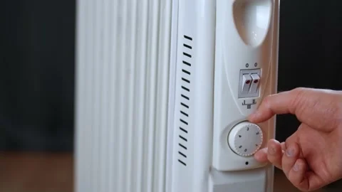 Man hand turn on button on thermostat of electrical heater radiator to control Stock Footage 233594608