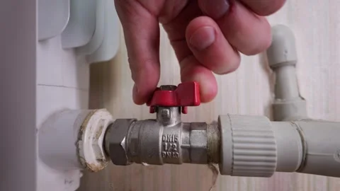 Man Hand Turning Red Valve on Radiator Pipe to Shut Off Heating System Stock Footage 339212456