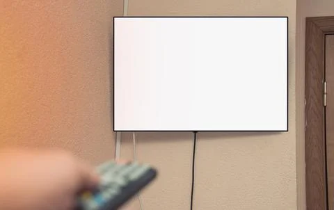 Man hand with tv remote control against empty white television screen Stock Photos