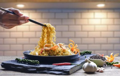 Man hand using chopsticks to picking up stir fry instant noodles spicy seaf.. Stock Photos