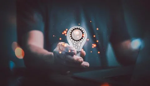 Man hand using computer and holding light bulb with a gear icon in it , The i Stock Photos