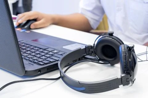 Man hand using keyboard and mouse to control laptop with headphone beside 写真素材