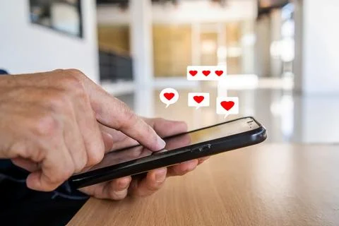 Man hand using smartphone with heart icon at office, He look message from l.. Stock Photos