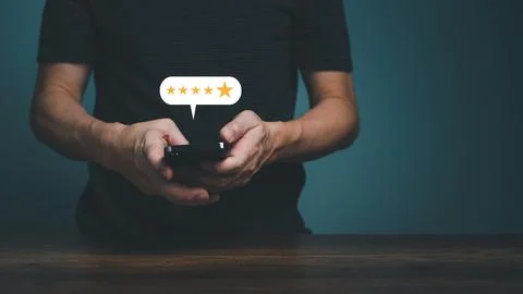 Man hand using smartphone with popup five star icon for feedback review satis Stock Photos