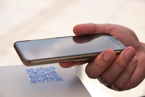 Man hand using the smartphone to scan the QR code in a bar table. Stock Photos