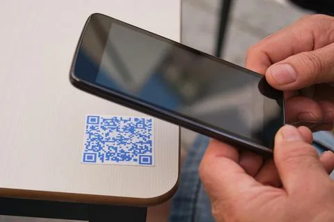 Man hand using the smartphone to scan the QR code in a bar table. Stock Photos