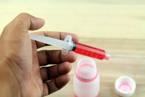 Man hand using syringe to draw sucking red medicine from bottle. Preaparing f Stock Photos