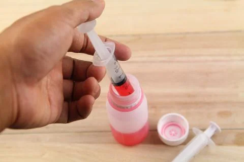 Man hand using syringe to draw sucking red medicine from bottle. Preaparing f Stock Photos