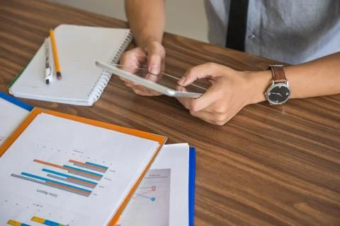 Man hand using tablet with financial document on desk Stock Photos