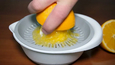 Man hand view while squeezing fresh orange fruit on juicer,healthy breakfast Stock Footage 143292618