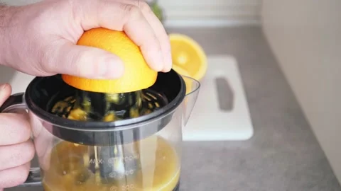 Man hand view while squeezing fresh orange fruit on juicer, healthy breakfast Stock Footage 151631337