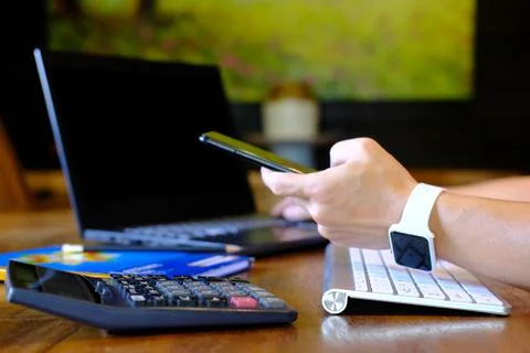 Man hand working on laptop computer on table and using smartphone home quar.. Stock Photos
