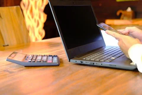 Man hand working on laptop computer on table and using smartphone home quar.. Stock Photos