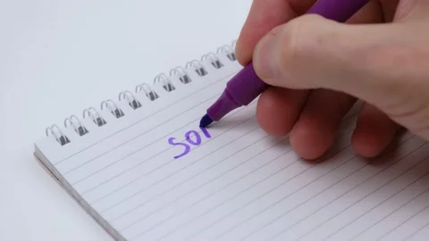 Man hand writes the word sorry with purple marker in notebook. close up. Stock Footage 224890700