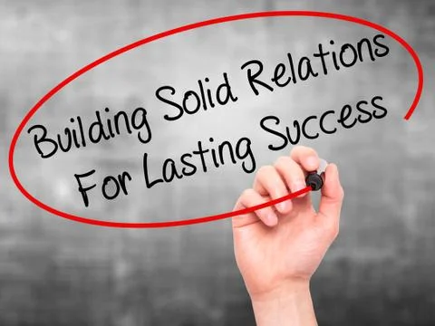 Man Hand writing Building Solid Relations For Lasting Success with black mark Fotos de archivo