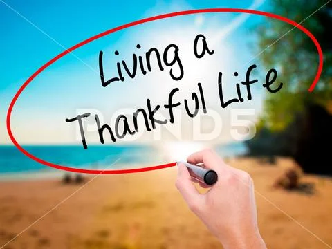 Man Hand writing Living a Thankful Life with black marker on vis Stock Photos
