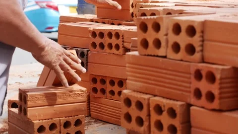 A man handles red bricks, arranging them carefully into a vehicle during a Vídeo Stock 314120239