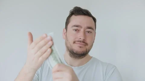 Man handling cash with a confident expression in an indoor setting Stock Footage 306260102