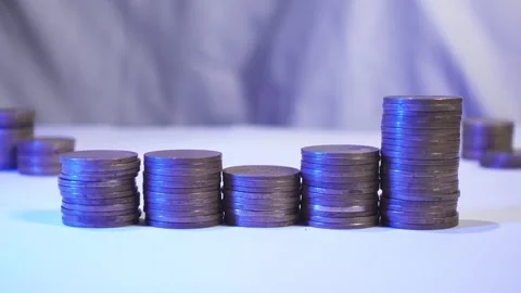 A man hand's adds gold coins to a stack on white background Stock Footage 287741804