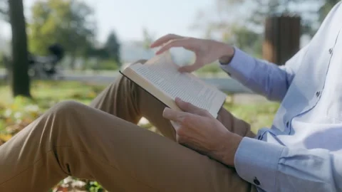 Man Hands and Book in Focus as He Reads Under a Tree Stock Footage 300249177