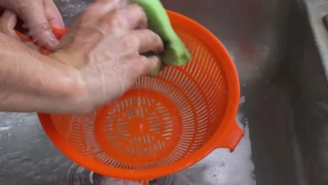 A man hands are washing a colander in a metal sink in close-up. Stock Footage 233444546