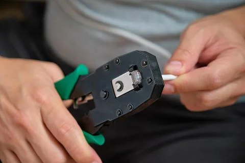 Man hands attaching net cable to RJ45 connector using data cable crimper. Foto stock