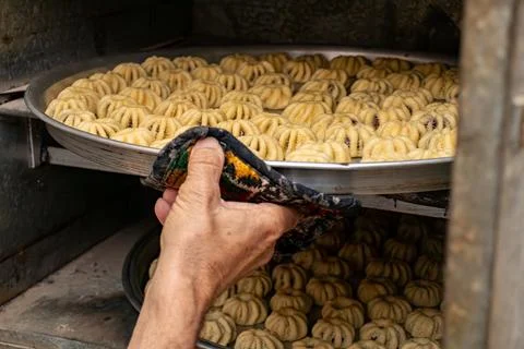 Man hands baking eid kahk in arabian oven Stock Photos
