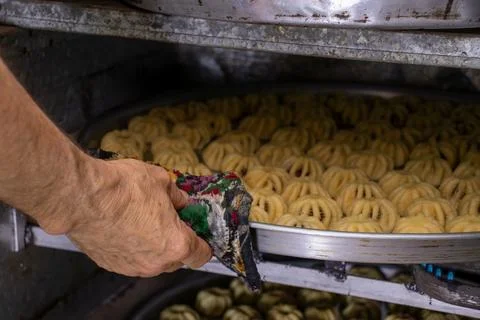 Man hands baking eid kahk in arabian oven Stock Photos