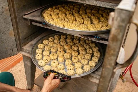 Man hands baking eid kahk in arabian oven Stock Photos