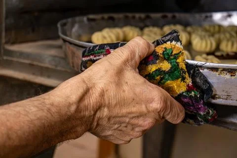 Man hands baking eid kahk in arabian oven Stock Photos