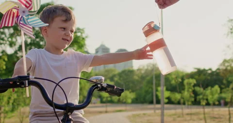 Man hands boy bottle of water after cycling training session Stock Footage 316764786