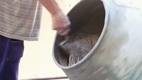 Man hands with a bricklayer spoon clean the mixer machine mouth in a close u Stock Footage 211541386
