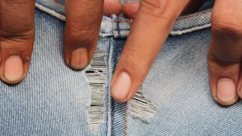 Man hands checking torn denim jeans at back seam while sitting Stock Footage 348579427
