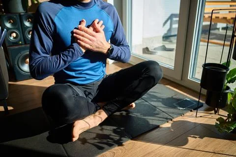 Man with hands on chest doing breathing exercise on mat at home Stock Photos