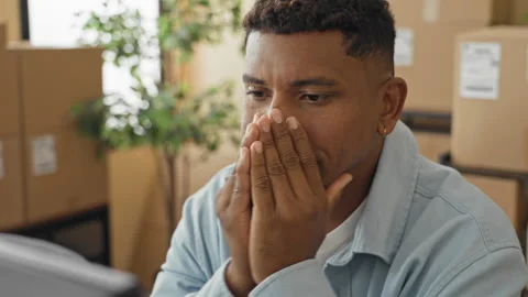 Man hands clasped to mouth, looking at computer amid stacked packages and b.. Stock Footage 337369746